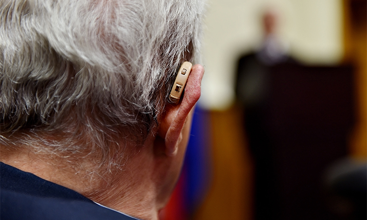 Detail shot with a hearing aid device used by old man during conference