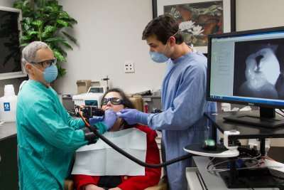 Michael Staninec (left), DDS, PhD, and Jacob Simon, a staff research associate, test out a device that uses optical coherence tomography, which uses near-infrared light to view cavities in teeth better than traditional X-rays. Credit: Susan Merrell