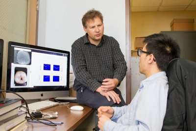 Daniel Fried, PhD, speaks with Leon Chung, a dental research fellow in his lab. Credit: Susan Merrell