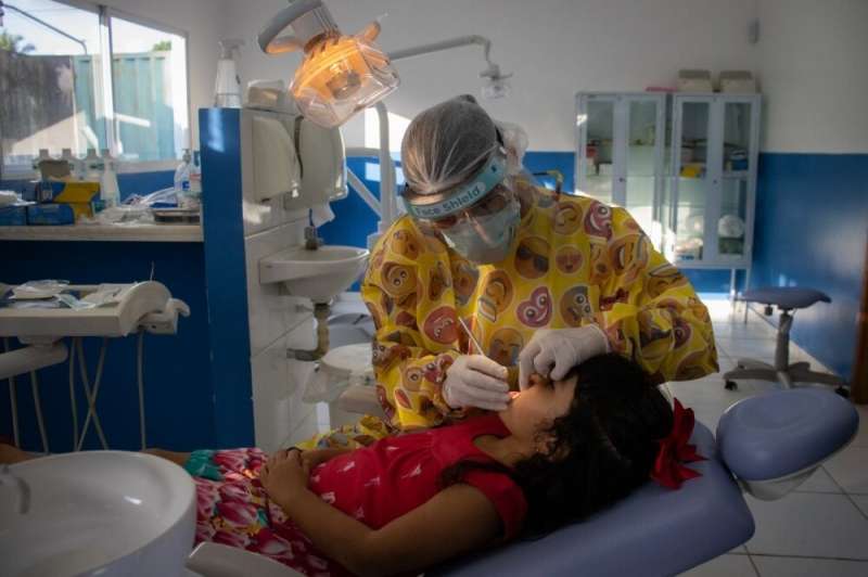 Researcher Jenny Abanto examines the teeth of a child included in the MINA study in Cruzeiro do Sul, Acre state, Brazil. Credit: Bárbara Prado