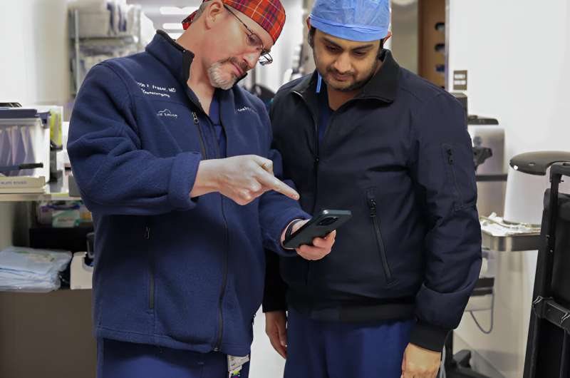 Justin Fraser, M.D., and Muhammed Fawad Ishfaq, M.D., are able to quickly review patient scans through their phones. Credit: Lily Wilder/University of Kentucky