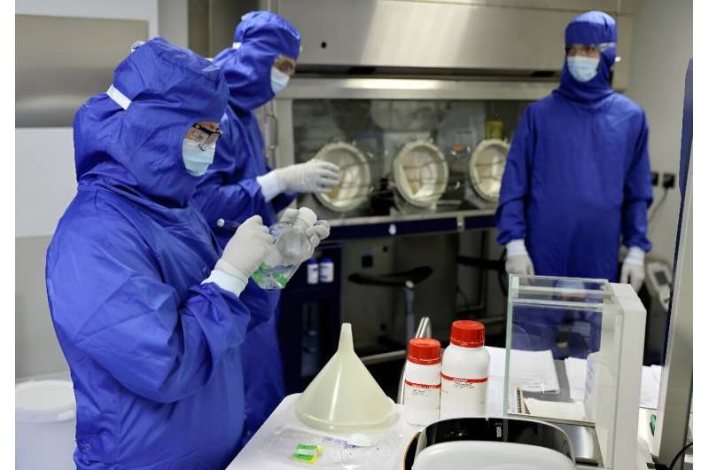 Lab technicians work on a process machine to produce CAR-T cells and RNA in the laboratory of French biopharmaceutical company C